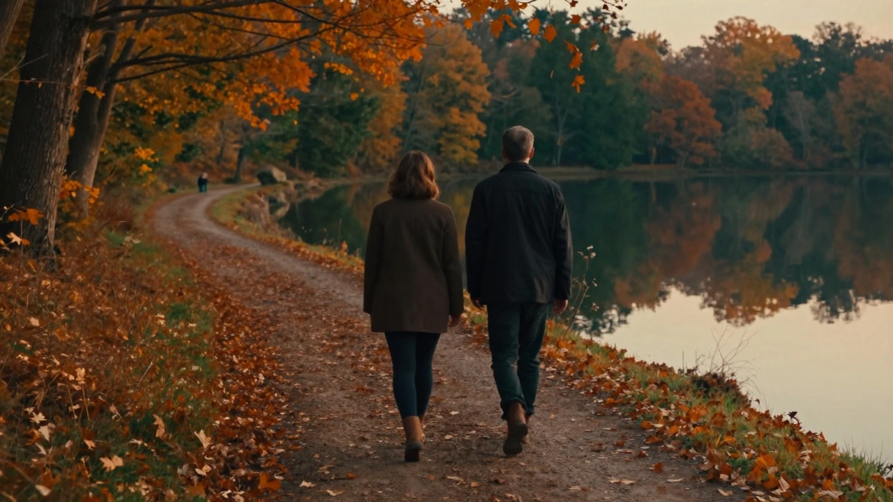 A couple walking silently along a lakeside trail in autumn, surrounded by falling leaves.
