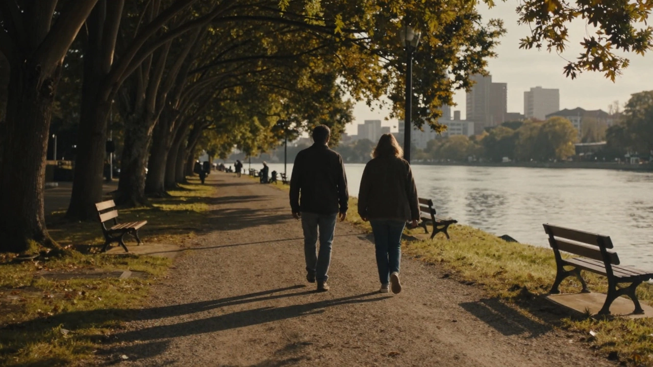Two individuals walking side by side along a riverside path at sunset, shadows long on the trail.